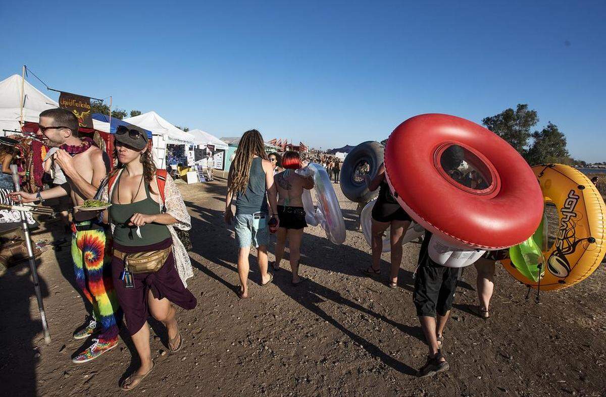 Festival goers head back to camp after playing in the water of Woodward Reservoir during the Symbiosis gathering in Oakdale Calif., on Thursday, September, 17, 2015. 