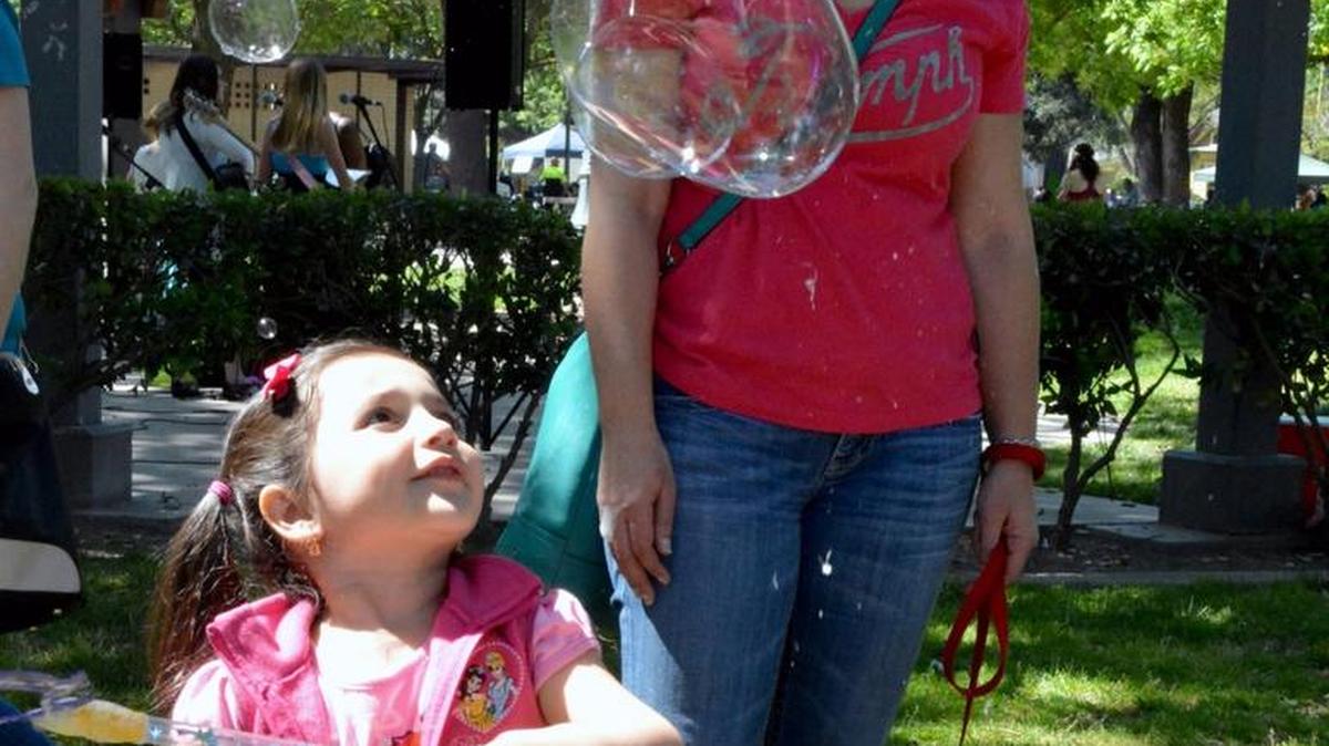 Sandra Molina watches daughter Liliana, 3, make bubbles at Earth Day 2015.