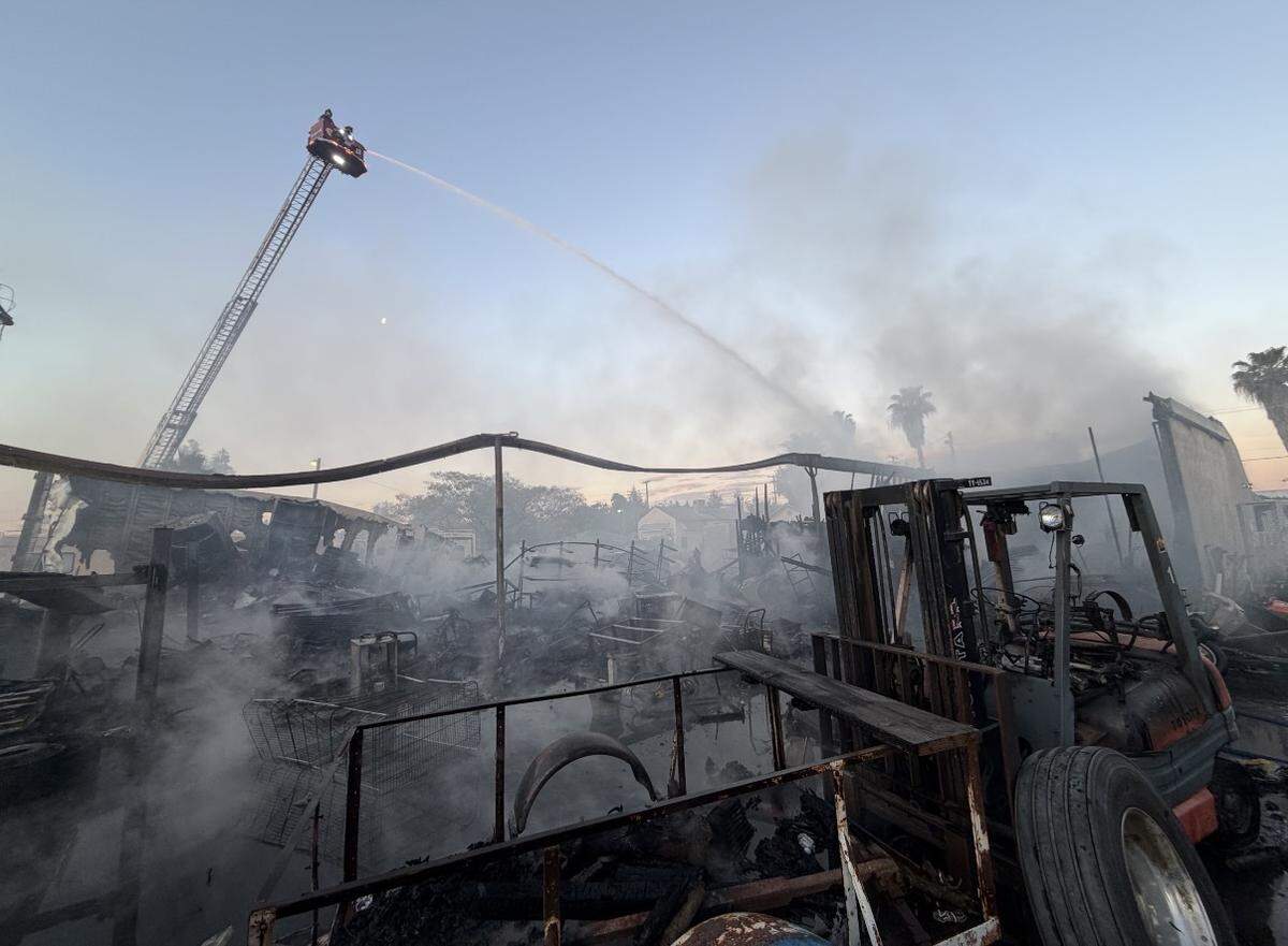 A ladder truck sprays water over the smoldering remains of a structure fire on Beard Avenue in Modesto after crews brought the blaze under control.