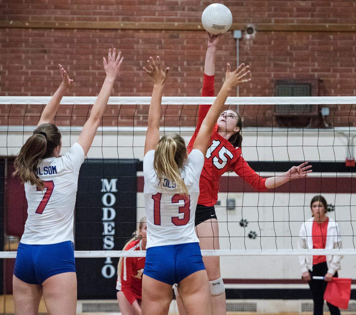 Modesto’s Hannah Scott floats the ball over Folsom’s Sydney Radell (7) and Lauren Thompson (13) during the Sac Joaquin Section playoff game at Modesto high School in Modesto, Ca., on Tuesday, Oct. 23, 2018.