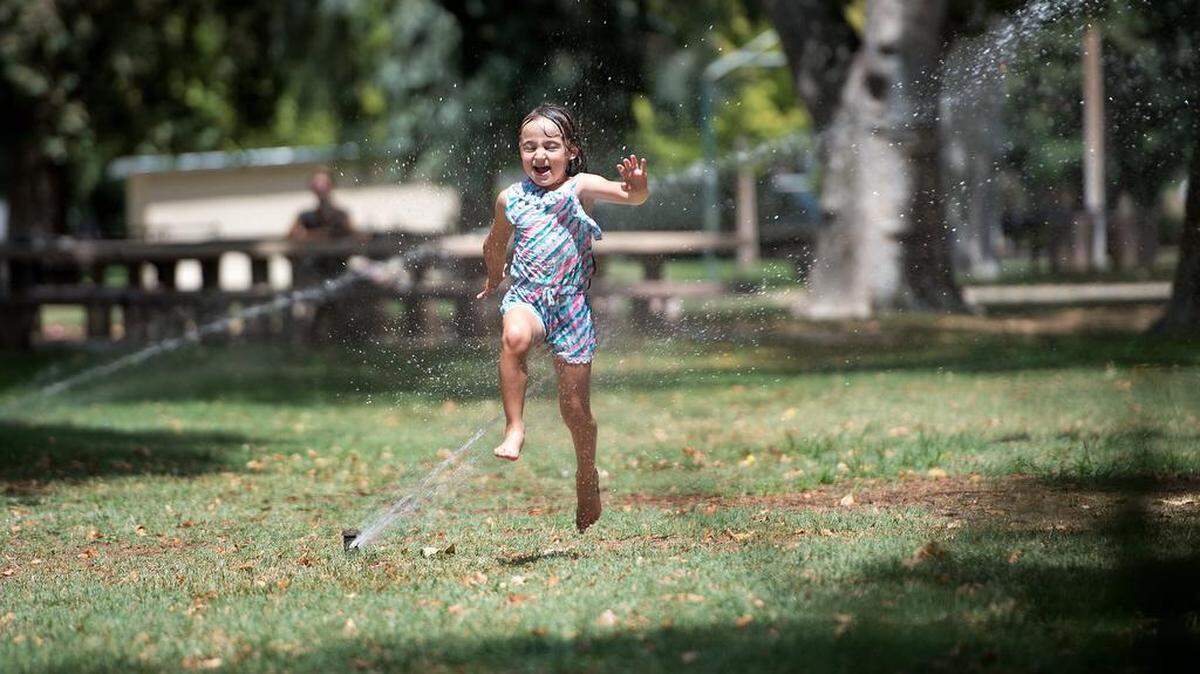 Marina Gutierrez, 5, runs through the sprinklers at Crane Park as her mother watches in Turlock, Calif., Friday, July 13, 2018. 