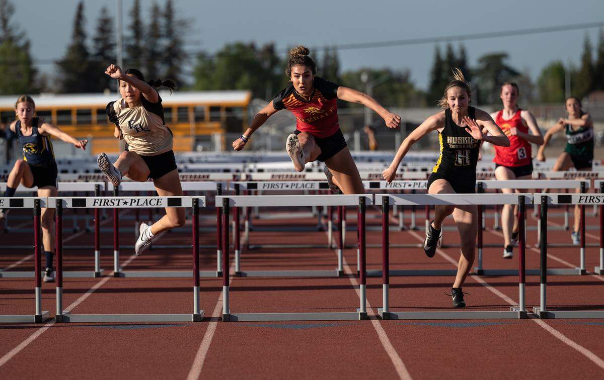 Kylie Nunes of Oakdale, middle, outruns Enoch’s Lindsey Strong, left, and Hughson’s Logann Meyer, right, for the victory in the girls 110 hurdles race at the Stanislaus County Championships on Friday, March 18, 2022, at Riverbank High School in Riverbank, Calif.