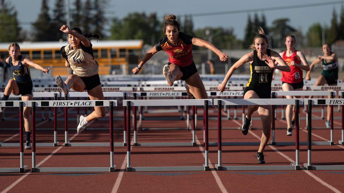 Kylie Nunes of Oakdale, middle, outruns Enoch’s Lindsey Strong, left, and Hughson’s Logann Meyer, right, for the victory in the girls 110 hurdles at the Stanislaus County Championships on Friday, March 18, 2022, at Riverbank High School in Riverbank, Calif.