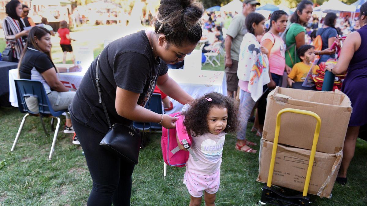 Ratana Neay helps her 3-year-old daughter, Chloe Horn, with her backpack during a giveaway in Modesto, Calif., in 2019