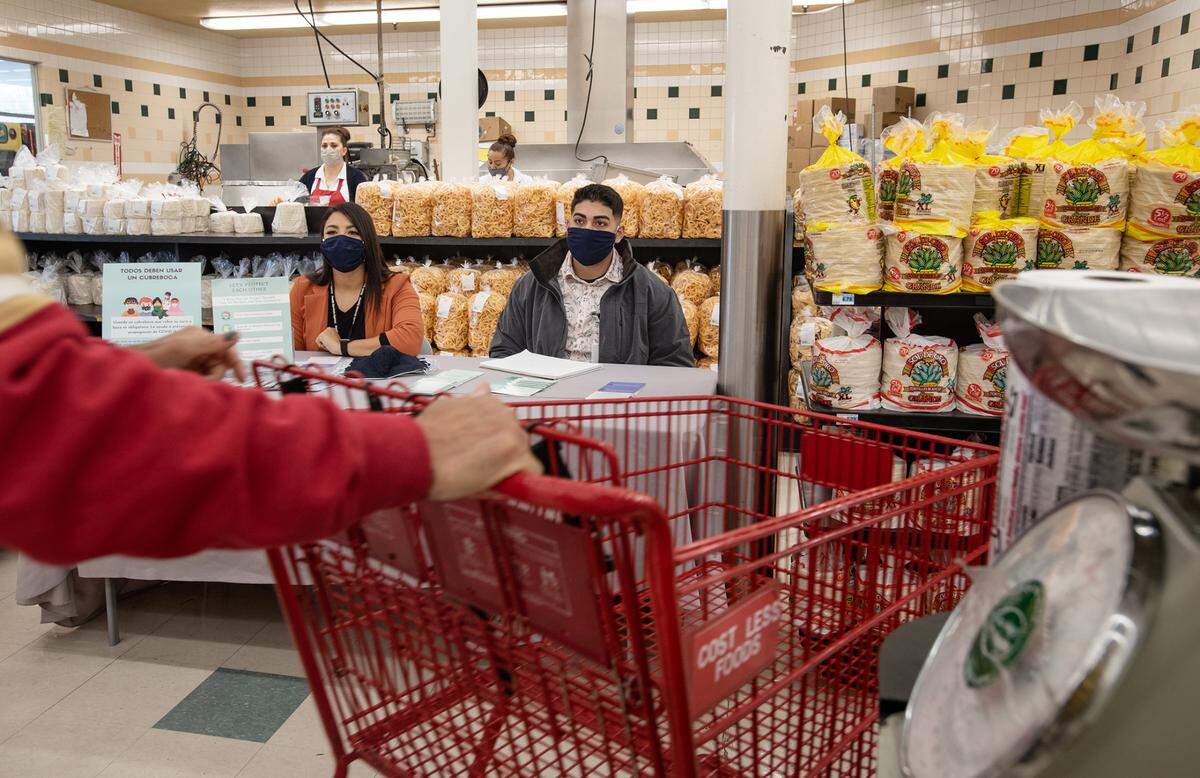 Stanislaus County Health Services Agency community outreach staff members Isabel Hernandez, left, and Satjinder Boyal, right, talk with shoppers about COVID-19 at Cost Less supermarket in Ceres, Calif., on Tuesday, Nov. 24, 2020.