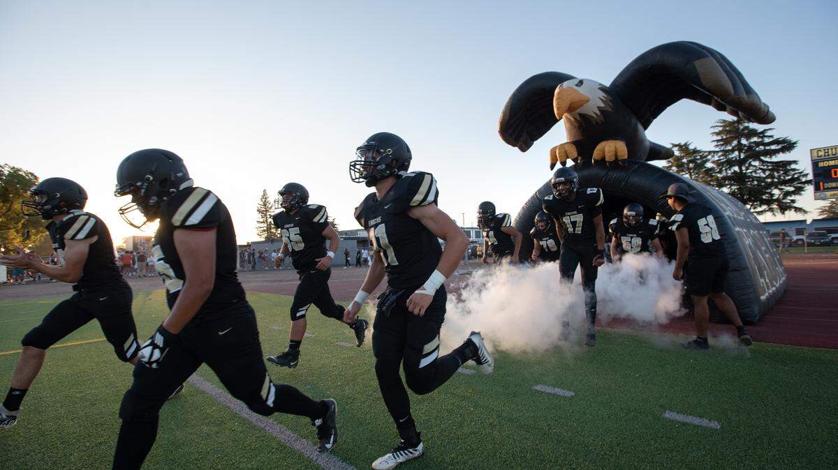 Enochs players run out of the eagle tunnel before the start of the Sylvan Bowl with Beyer at Downey High School in Modesto, Calif., on Friday, August 19, 2022.