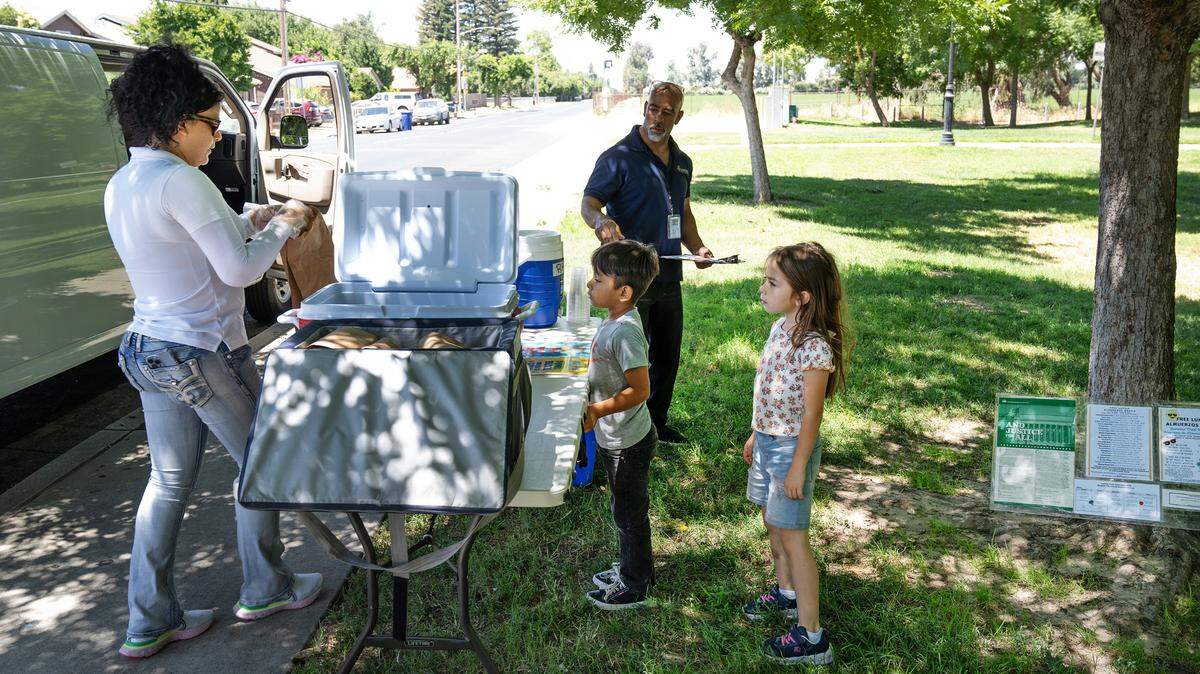 Nutrition services employee Lilianna Trujillo, left, serves up lunch to children during Modesto City Schools’ summer lunch program at Mark Twain Park on California Avenue in Modesto, Calif., Tuesday, June 25, 2024.