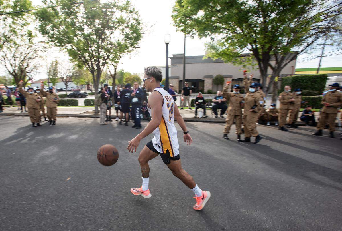 Mark Anthony Bautista bounces a basketball as he finishes the half marathon during the Modesto Marathon in Modesto, Calif., on Sunday, March 27, 2022.
