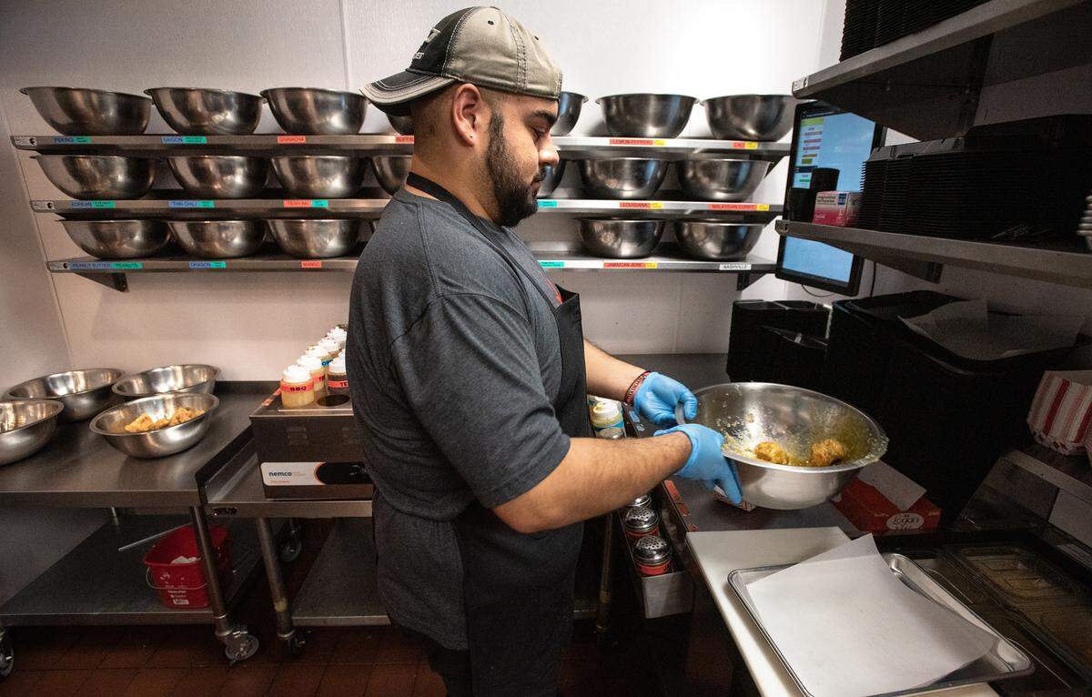 Cook Bryan Gaspar prepares garlic parmesan wings at Fire Wings restaurant in Turlock, Calif., on Thursday, June 9, 2022.