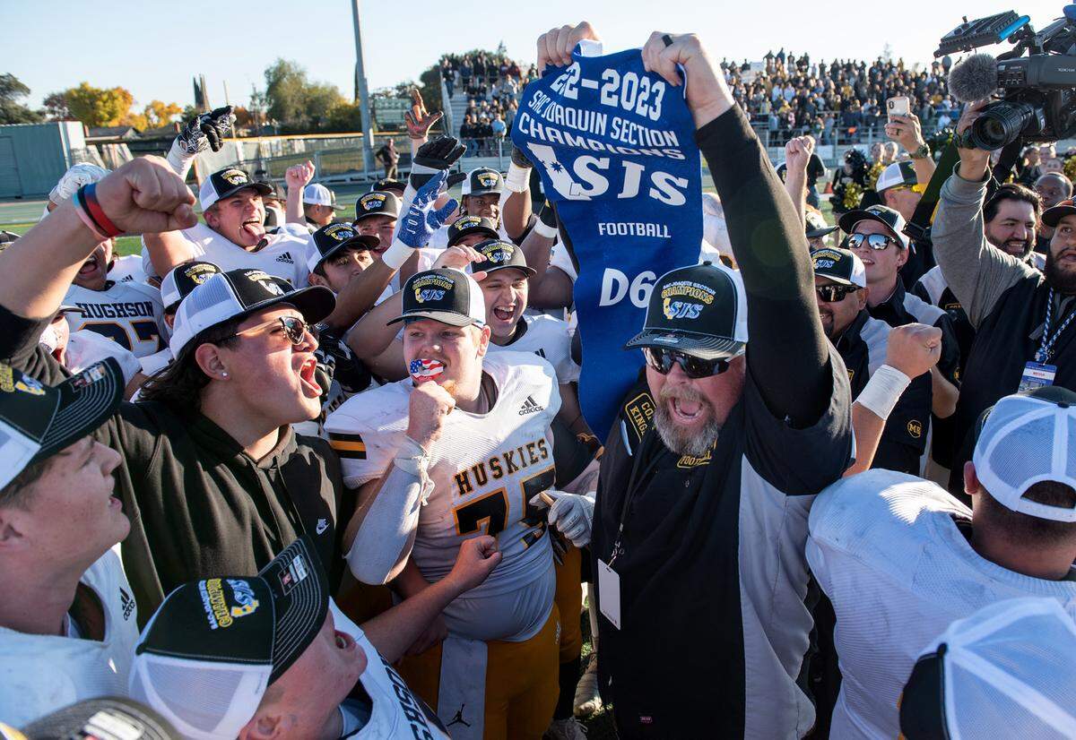 Hughson coach Shaun King holds up the section banner with his team after their 14-13 victory over Summerville during the Sac-Joaquin Section Division VI championship game at St. Mary’s High School in Stockton, Calif., Saturday, Nov. 26, 2022.