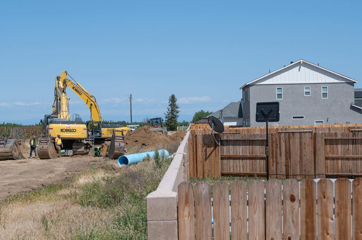 Workers install utility pipe in the Villages of Patterson development in Patterson, Calif., on Tuesday, April 12, 2022.
