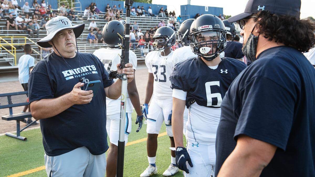 Downey coach Jeremy Plaa, left, talks with coaches and players before a pre-season scrimmage at Downey High School in Modesto, Calif., on Friday, Aug. 13, 2021.