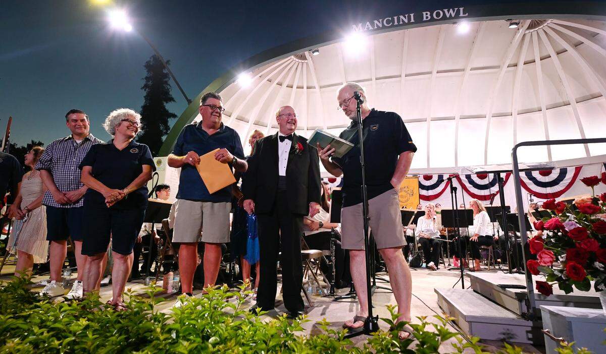 MoBand board members present retiring conductor George Gardner, second from right, with a gift for his 46 years of leadership during his final performance at Mancini Bowl in Graceada Park in Modesto, Calif., Thursday, July 11, 2024.