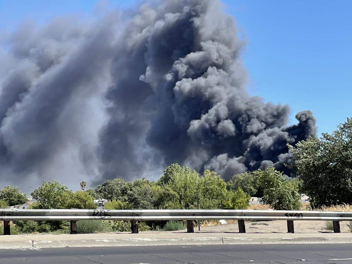 Smoke billows from a fire at an auto salvage yard on Crows Landing Road in south Modesto on Sunday afternoon, May 29, 2022.