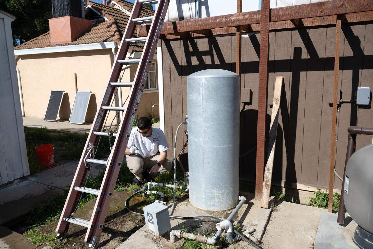Geoanalytical Laboratories technician Logan Davis draws a water sample from the domestic well on the property of the Petersen family in 2025. 