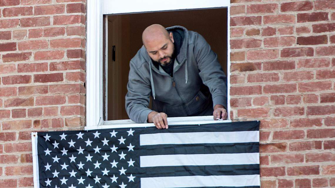 Jorge Castaneda hangs a flag from his business window in downtown Newman, Calif., Thursday, Jan. 3, 2019. A procession carrying slain officer Ronil Singh’s body is set to go from Modesto to Newman Friday morning. An honor guard visitation will be held at the West Side Theatre on Main Street from 9 a.m. to noon.