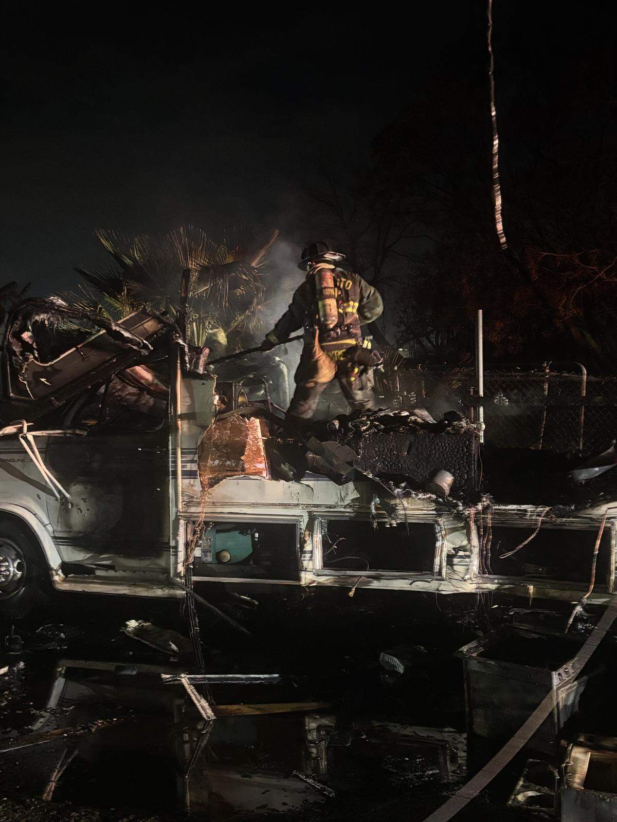 A firefighter works atop the burned RV after crews secured downed power lines in south Modesto.