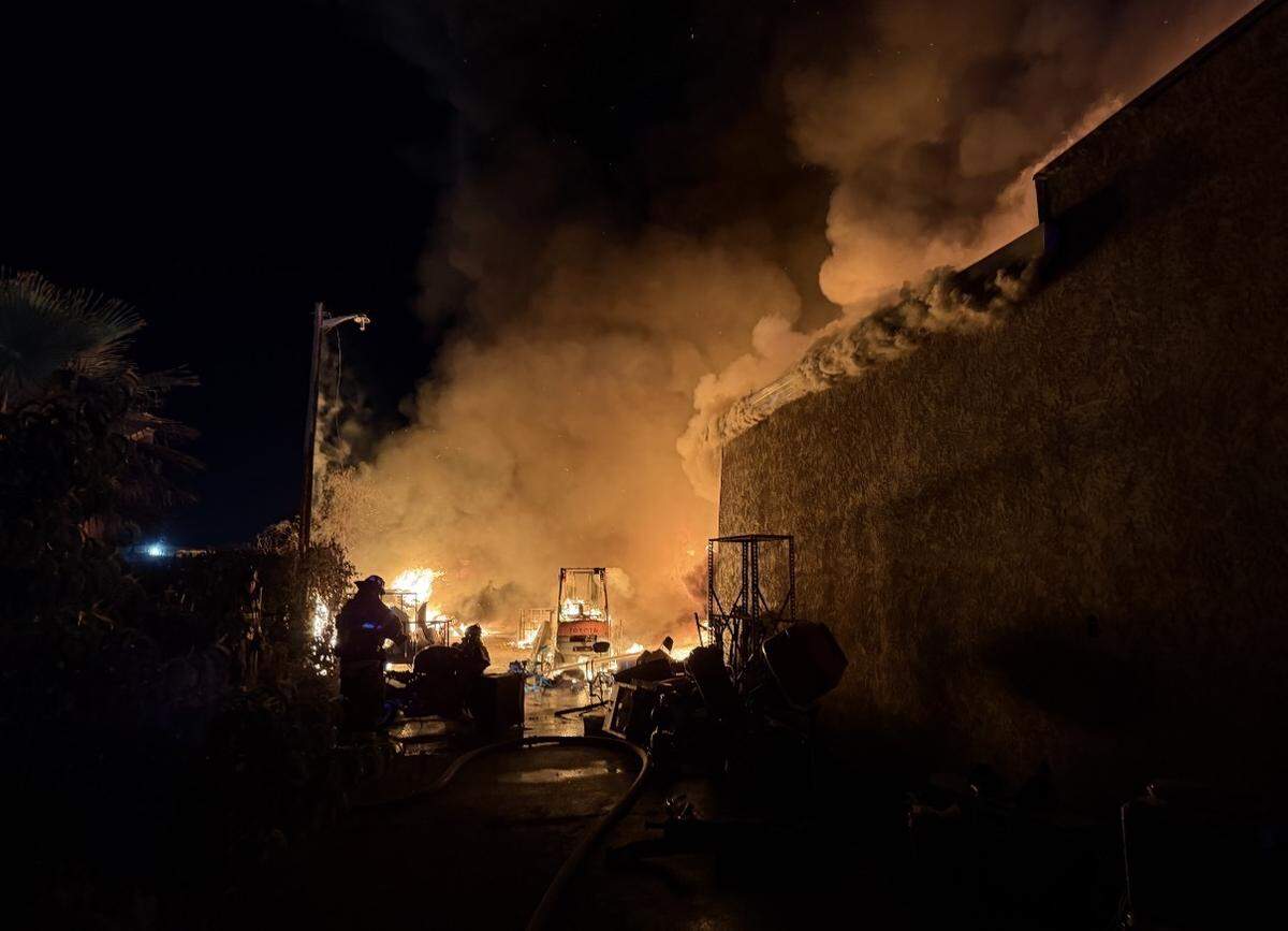 Firefighters battle a large structure fire in the 500 block of Beard Avenue in Modesto early Wednesday morning, where flames engulfed a commercial structure behind nearby homes.