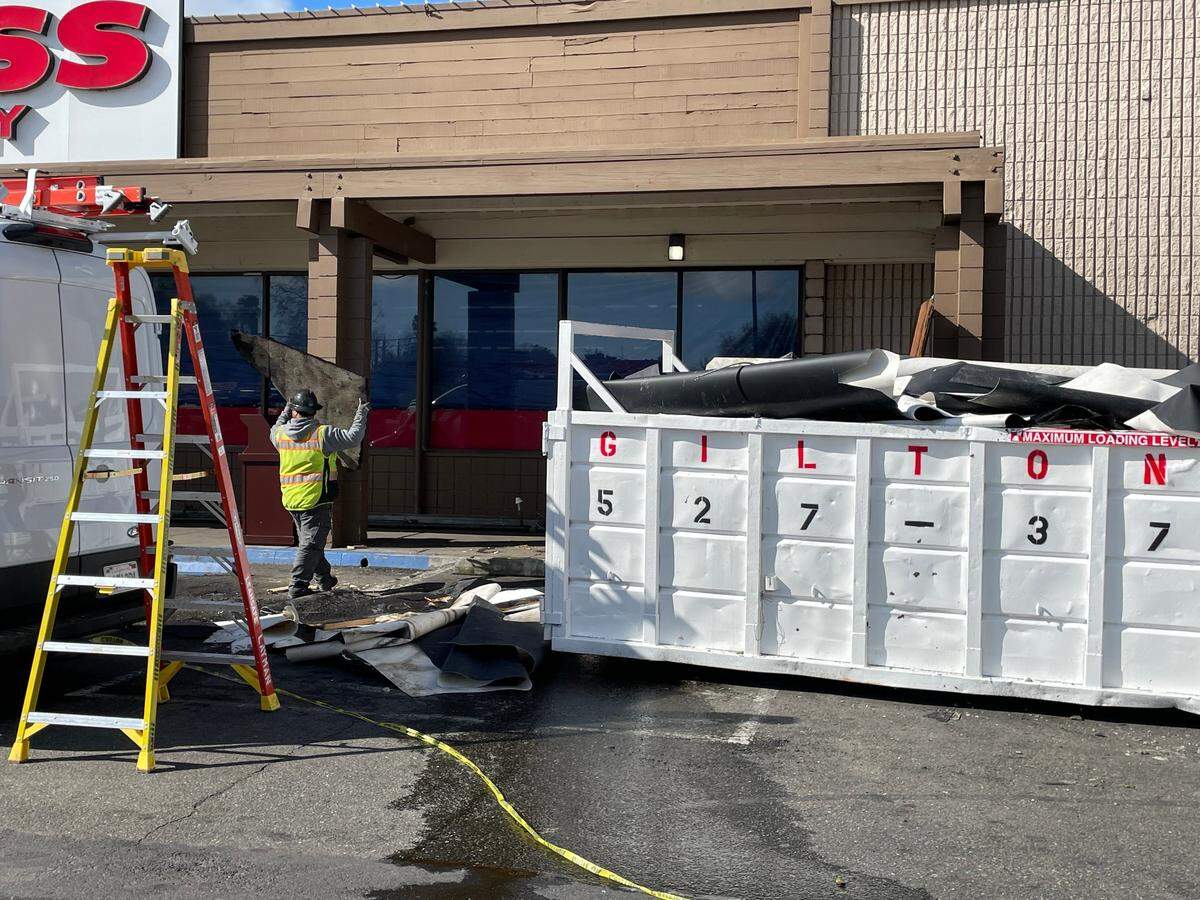 A worker hauls a part of the roof after it collapsed at Cost Less Food Company in Oakdale on Monday, March 17.