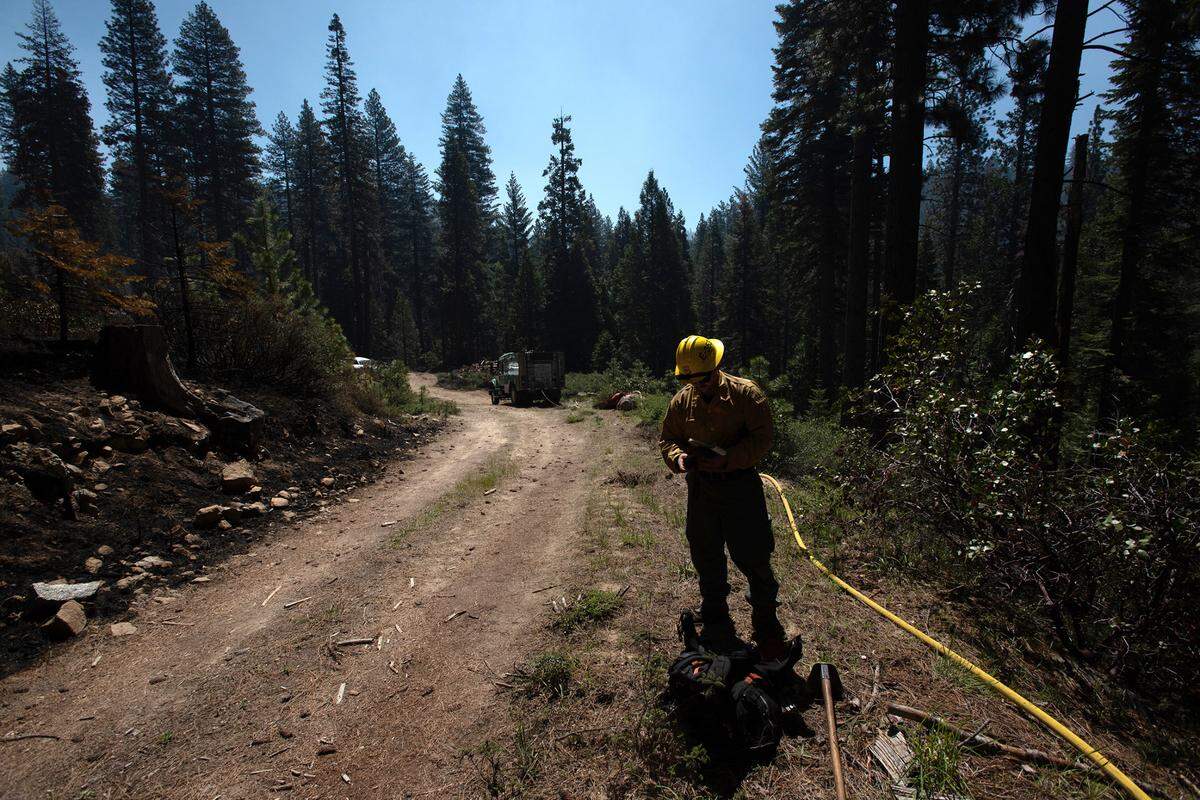 Eldorado National Forest firefighter Zachary Wasilchin takes a weather reading as he and other firefighters mop up hotspots after a prescribed burn in the Stanislaus National Forest near Strawberry, Calif., on Friday, May 20, 2022.
