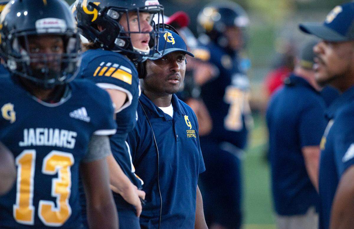 Gregori coach Lamar Wallace, middle, and players watch the defense from the sideline during the non-league game with Merced at Gregori High School in Salida, Calif., on Friday, August 26, 2022.
