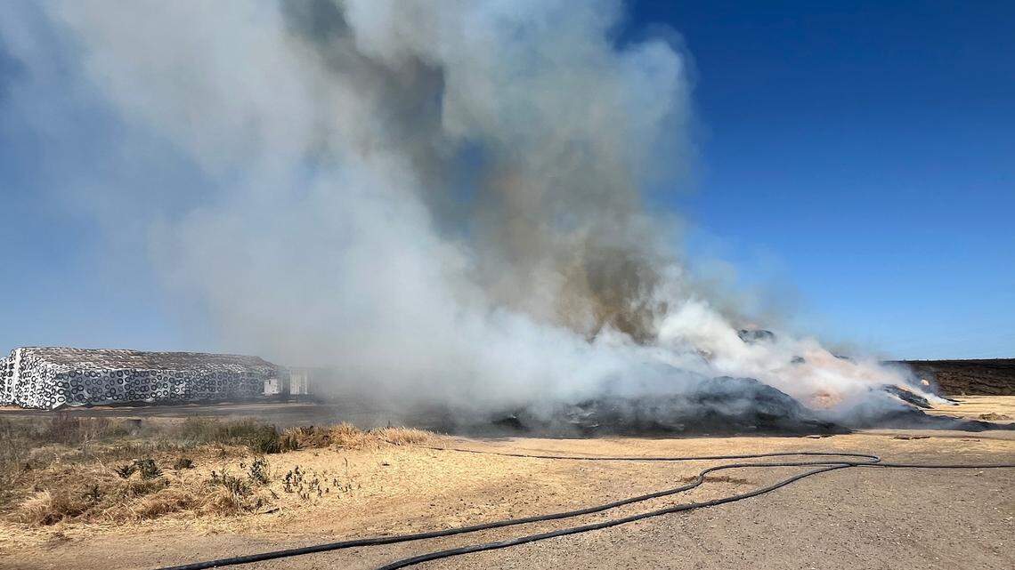 Firefighters work to contain a large haystack fire Wednesday morning near Oakdale.