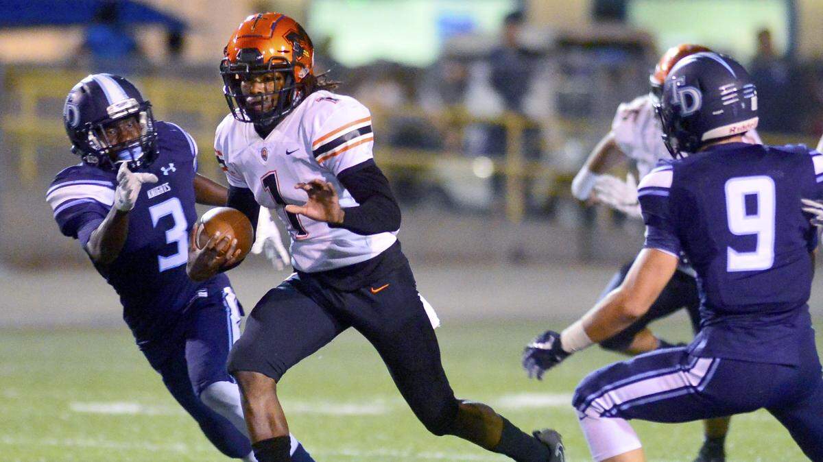 Merced quarterback Dhameer Warren (1) runs up the middle of the Downey defense during a game between Downey and Merced in Modesto at Downey High School on August 31, 2017.