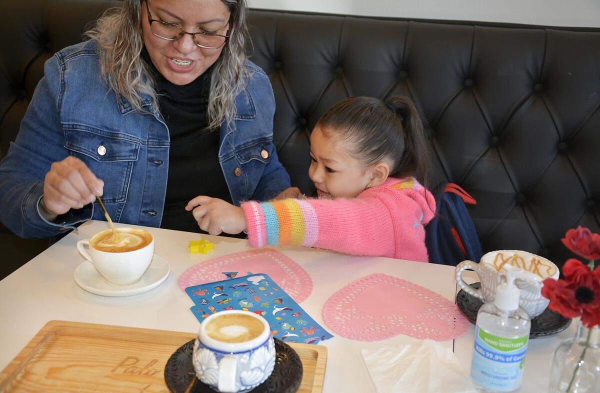 Alma Pineda of Oakdale and her daughter Elisaa Pineda, 3, enjoy a cup of caramel steamed milk at Palo Santo Cafe in Riverbank, Calif. Feb. 23, 2021.
