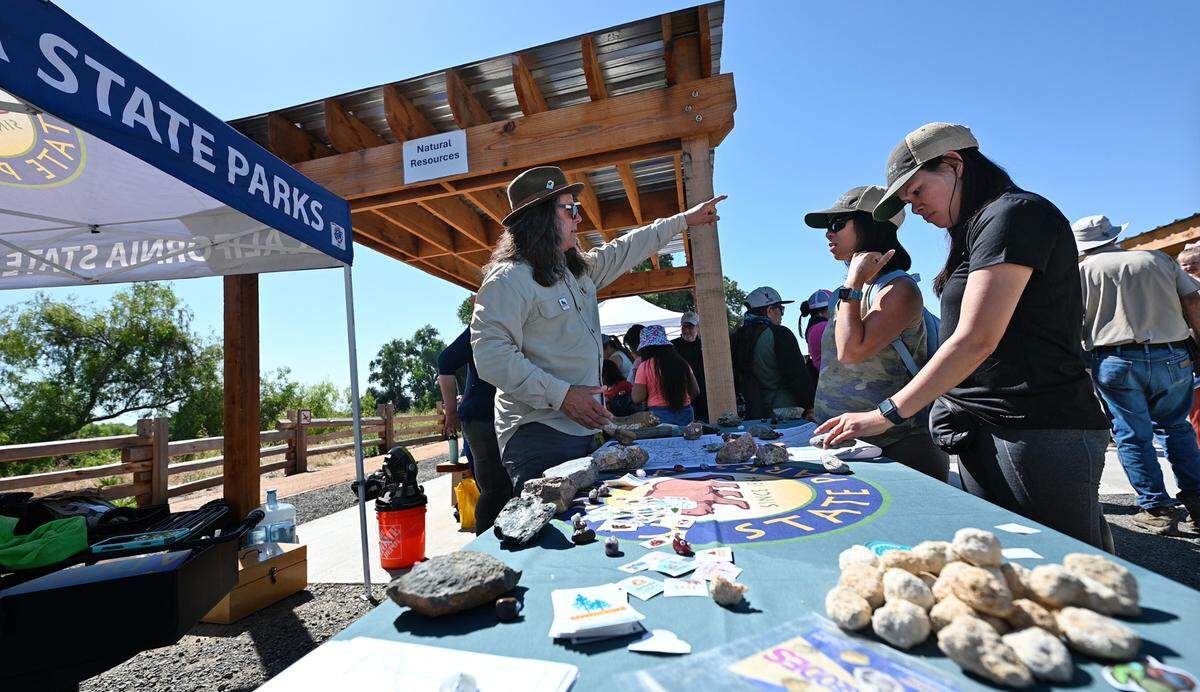 California State Parks Foundation director of programs Randy Widera, left, talks about the local geology with An Phan, middle, and Nhu-Y Phan, right, at opening day at Dos Rios State Park in Modesto, Calif., Wednesday June 12, 2024.