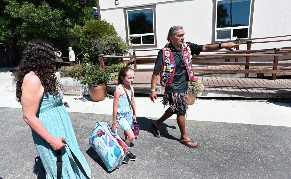 El cardiólogo Dr. Kavin Desai dirige a Emily Urias Ponce, de 9 años, a su cabaña en Camp Taylor en Grayson, California, el martes 11 de junio de 2024. El Dr. Desai ha sido el director médico de Camp Taylor desde su fundación en 2002.