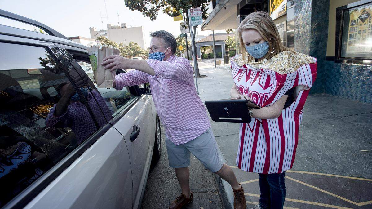 Executive director Kirstie Boyett, right, and Alan Zacharias sell popcorn at the State Theatre in Modesto, Calif., on Friday, May 1, 2020.