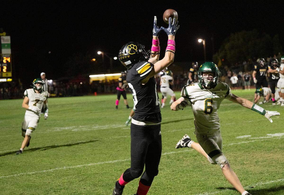 Hughson’s Bryce McDaniel (13) makes a sideline catch past Sonora defender Steven Morfoot during the Trans Valley League game in Hughson, Friday, Oct. 11, 2024.