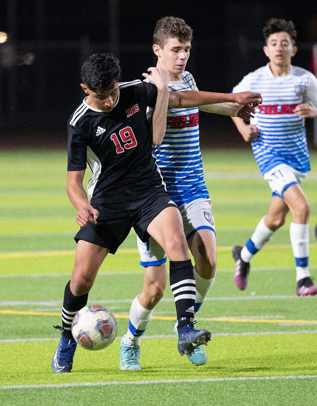Modesto’s Leonardo Avalos, (19) and Folsom’s Blake Garcia battle for the ball during the Sac-Joaquin section playoff game at Downey High School in Modesto, Calif., on Thursday, Feb. 10, 2022. Modesto won the first-round game 3-0.
