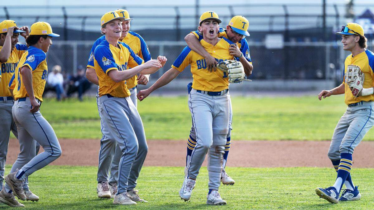 Turlock players mob outfielder Mason Baker after Baker threw out Downey runner Jaxen Rowland at the plate to end the game at Downey High School in Modesto, Calif., Friday, April 12, 2024. Turlock won the game 3-2.