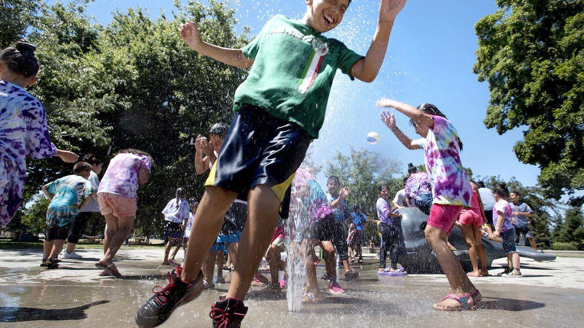 In this file photo, Children from the Modesto Parks and Recreation summer camp run through the splash fountains at Marshall Park in Modesto, Calif.