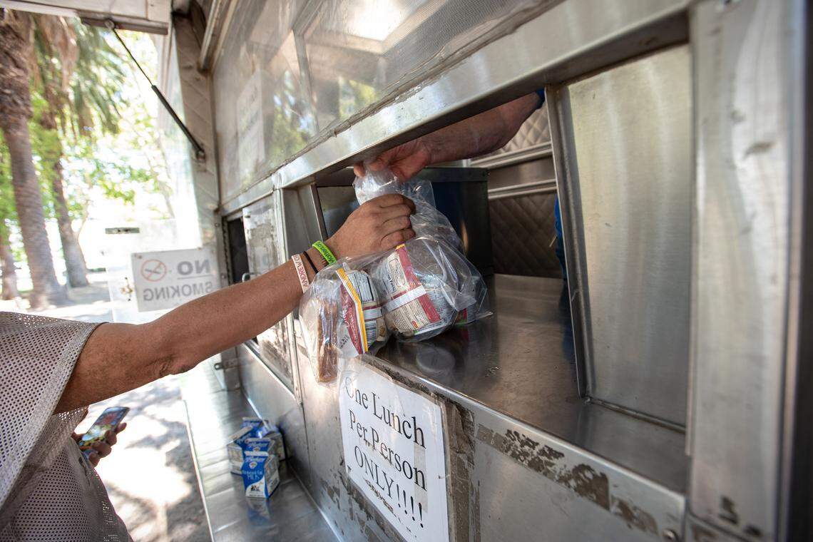 Brian (first name only) picks up lunch and bags of potatoes from a United Samaritans Foundation’s food truck at Mono Park in Modesto, Calif., on Friday, June, 24, 2022.
