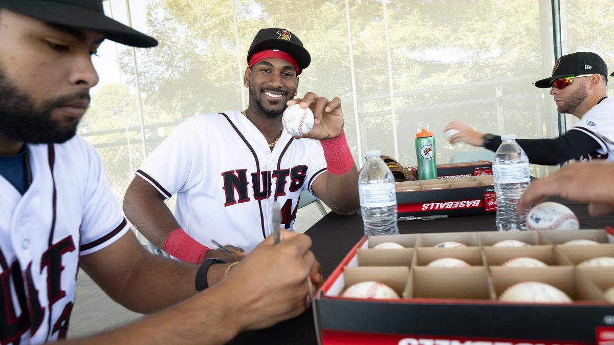 Modesto Nuts players Pedro Da Costa Lemos, left, and Lazaro Montes, middle, sign baseballs with teammates during media day at John Thurman Field in Modesto, Calif., Tuesday, April 2, 2024.