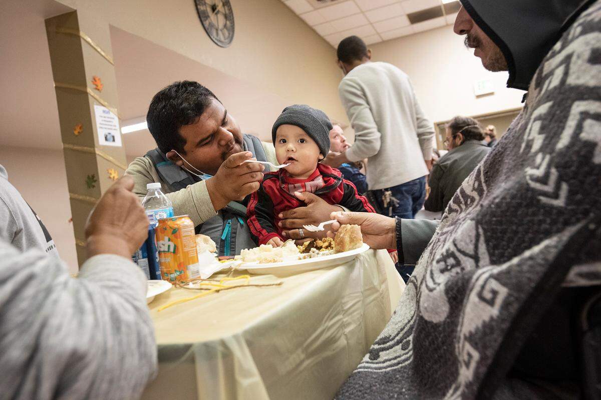 Ricardo Rojas feeds his son Liam, 1, during the Great Thanksgiving Banquet & Bundle-Up at the Modesto Gospel Mission in Modesto, Calif., on Wednesday, Nov. 24, 2021.