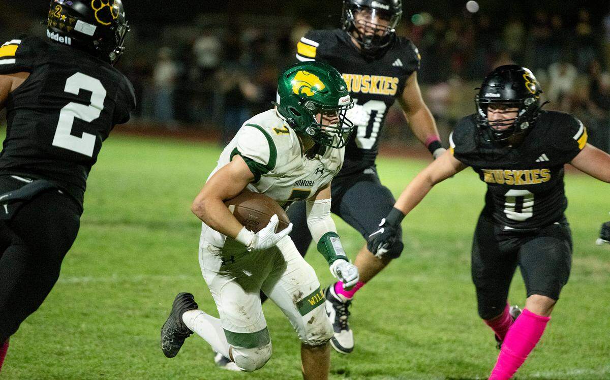 Sonora’s Cash Byington weaves through Hughson defenders on a run during the Trans Valley League game in Hughson, Friday, Oct. 11, 2024.