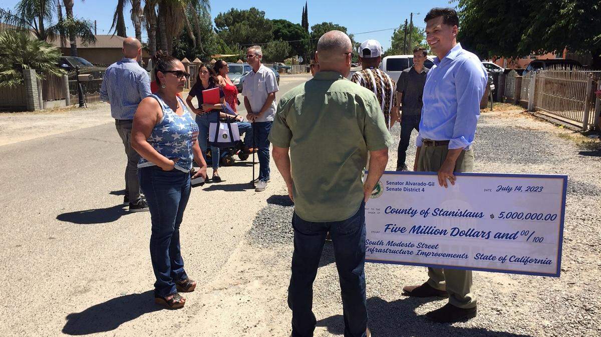 Stanislaus County Board of Supervisors Chairman Channce Condit holds a ceremonial check Friday while talking with constituents about state funding for south Modesto street improvements. State Sen. Marie Alvarado-Gill secured the $5 million in funding.