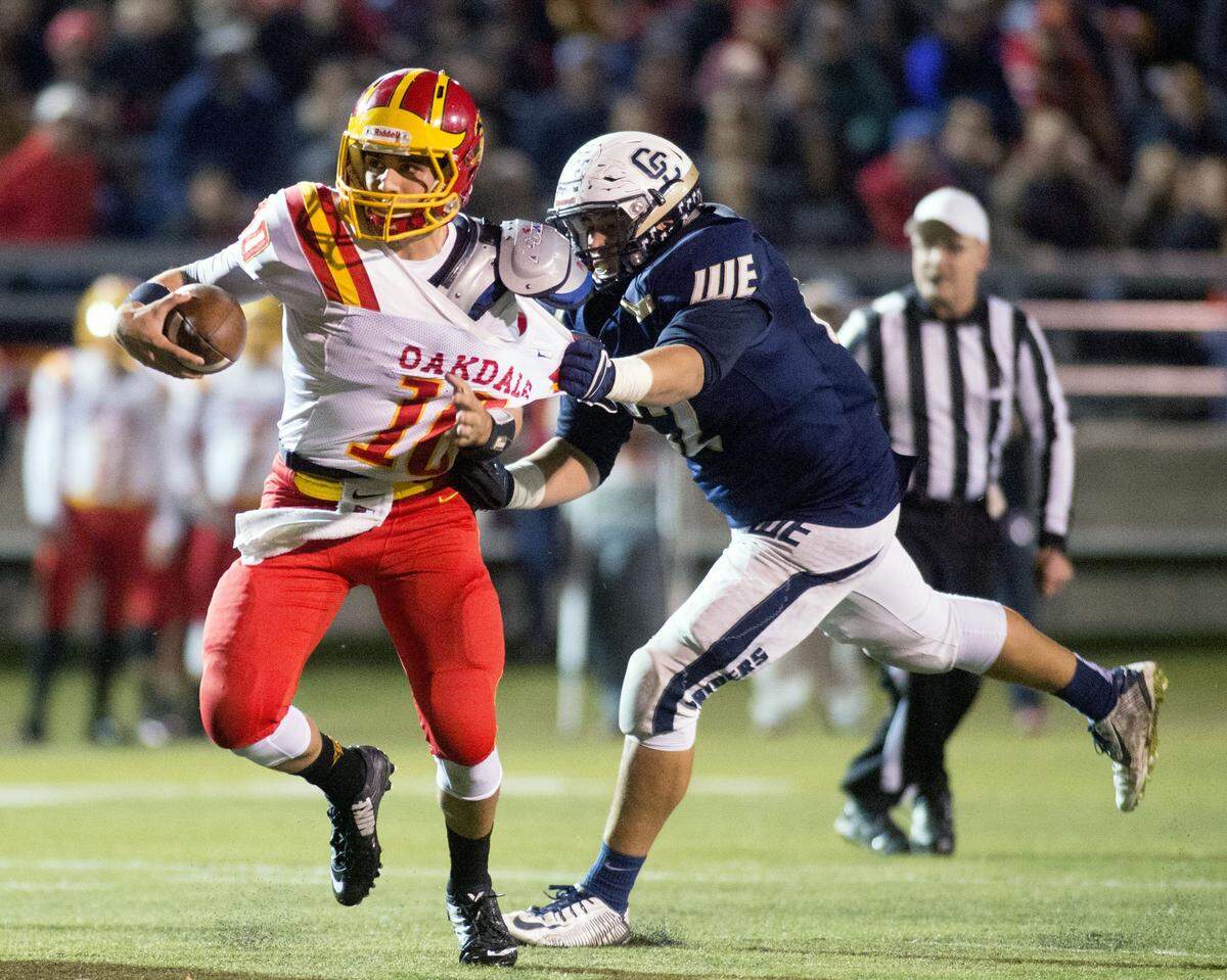 Oakdale quarterback Adam Olsen is grabbed by Central Catholic's Javier Canela during the Division III Championship game between Oakdale and Central Catholic, where Central Catholic won 21-7 at Lincoln High School in Stockton on Dec. 4, 2015.  
