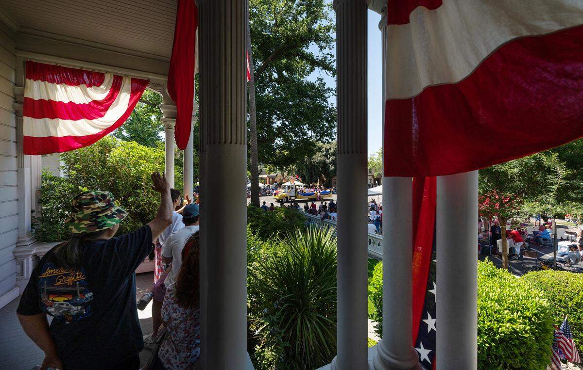 People watch the Independence Day Parade from the McHenry Mansion porch in Modesto, Calif., Tuesday, July 4, 2023.