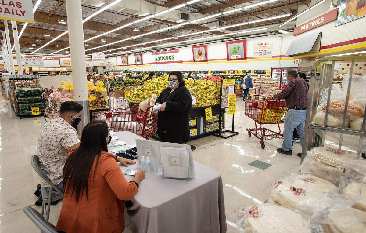 Stanisilaus County Health Services Agency communinty outreach staff members Isabel Hernandez and Satjinder Boyal talk with Elaine Hensley about COVID-19 at Cost Less supermarket in Ceres, Calif., on Tuesday, Nov. 24, 2020.
