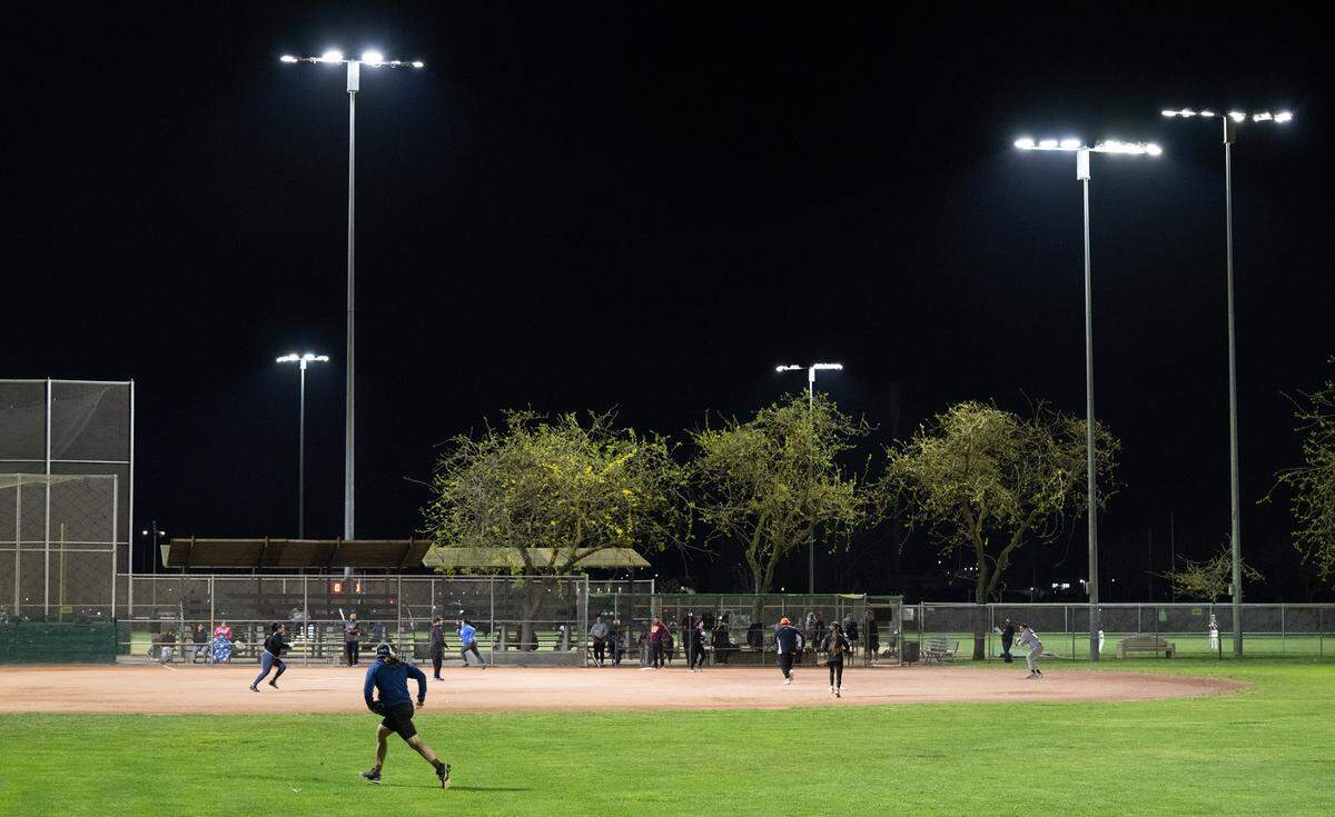 Adults play in a co-ed softball league under new LED lights at Pedretti Park in Turlock, Calif., Thursday, March 28, 2024. The new LEDs are more than 50% brighter than the metal halide lighting installed in the early 1980s.