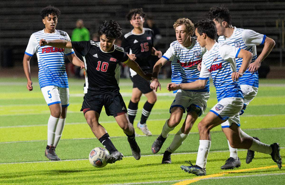 Modesto’s Alexis Luna tries to evade Folsom defenders near the goal during the Sac-Joaquin section playoff game at Downey High School in Modesto, Calif., on Thursday, Feb. 10, 2022. Luna scored all three goals in Modesto’s 3-0 victory.