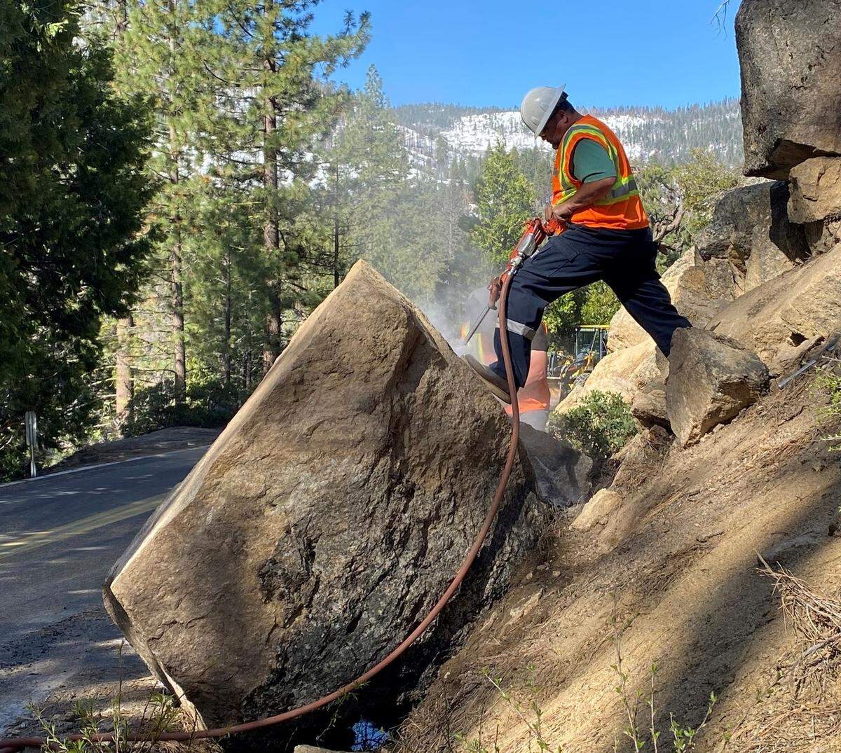 Equipment operator Dewayne Tillery breaks up a boulder amid the snow that blocked upper Highway 108. The California Department of Transportation had plowed it as far east as Kennedy Meadows as of May 15, 2023.