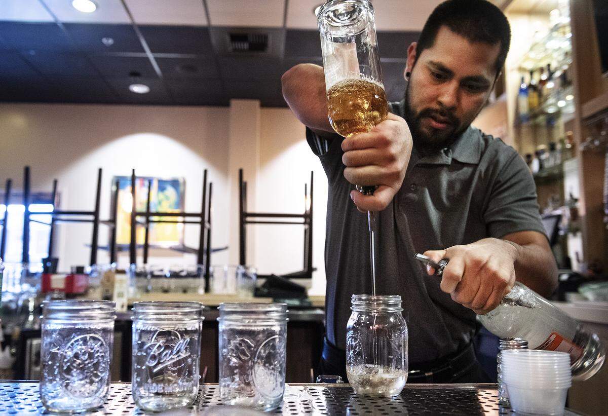 Daniel Zepeda makes mixed drinks to go with a take-out order at La Parilla in Modesto, Calif., on Saturday, March 21, 2020. The is allowing the sale of mixed drinks as long as it sold in a sealed container with food.