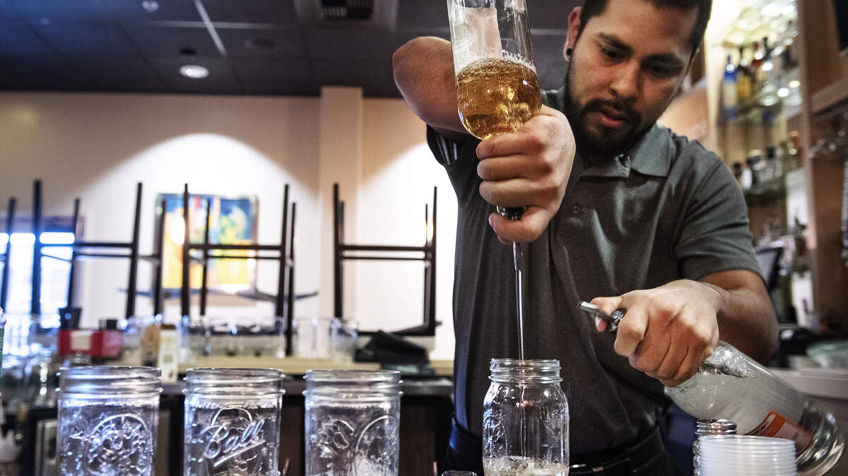 A bartender makes mixed drinks to go with a take-out order at La Parilla in Modesto in March 2020.