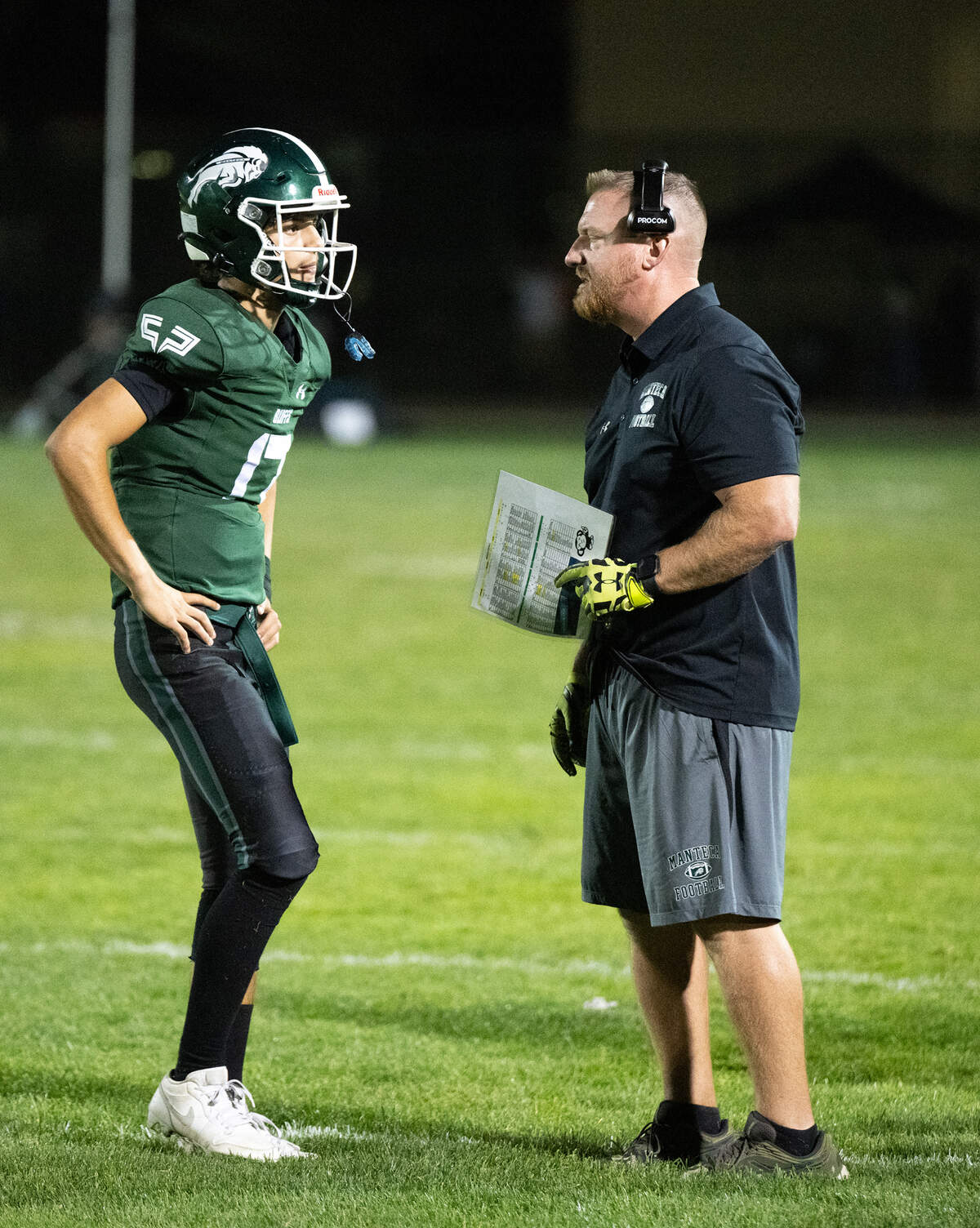 Manteca coach Mark Varnum talks with quarterback Owen Gully during the Valley Oak League game at Lathrop High School in Lathrop, Calif., Friday, Sept. 27, 2024.