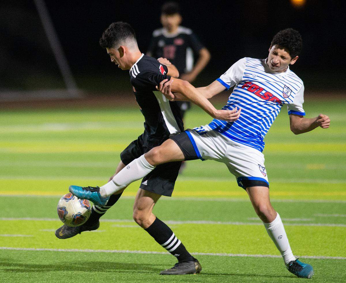 Modesto’s Adrian Silva Toro, left, and Folsom’s Rami Zantout battle for the ball during the Sac-Joaquin section playoff game at Downey High School in Modesto, Calif., on Thursday, Feb. 10, 2022. Modesto won the first-round game 3-0.